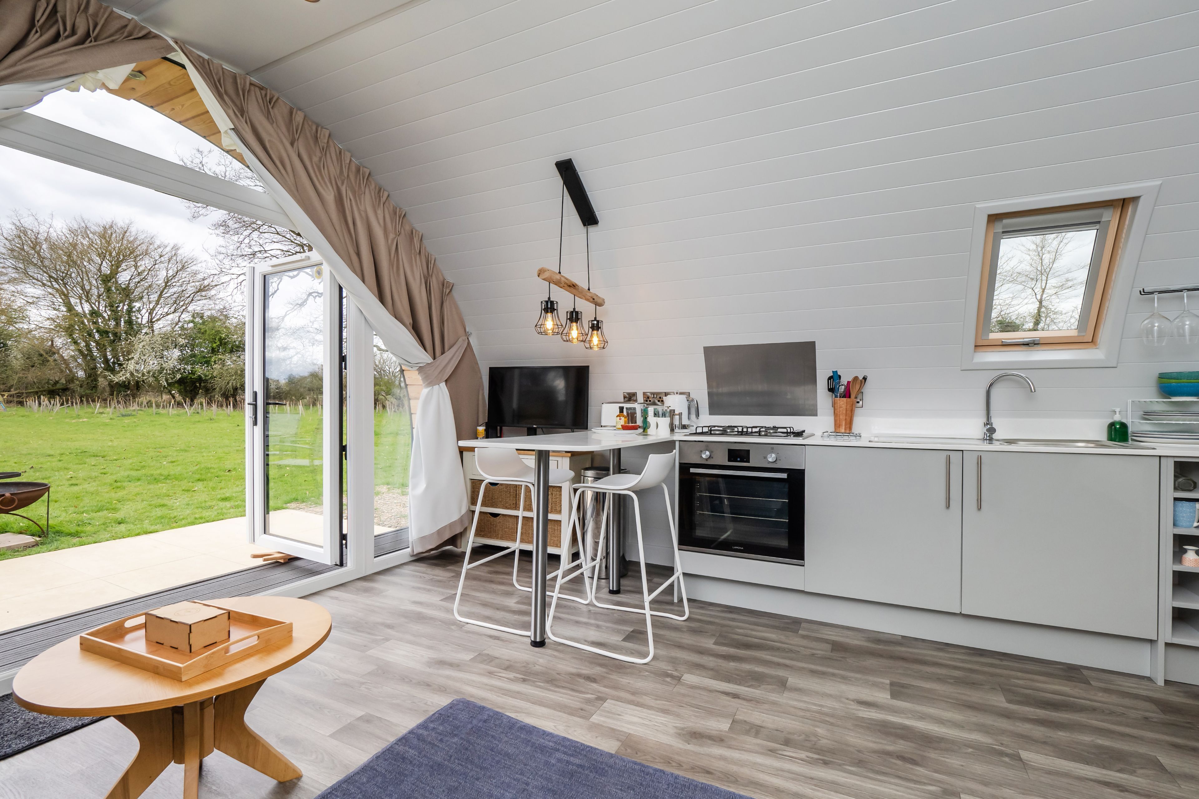 A modern kitchen with white cabinets, a built-in oven, and a large window.