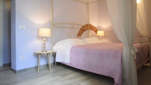 A four-poster bed with white linens, two bedside tables with lamps, and a canopy.