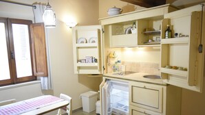 A compact kitchen with a refrigerator, sink, and wooden cabinets.
