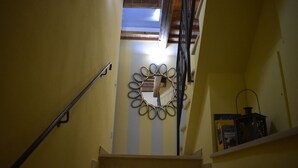 A staircase with a handrail, a wall-mounted circular decoration, and a shelf with items.