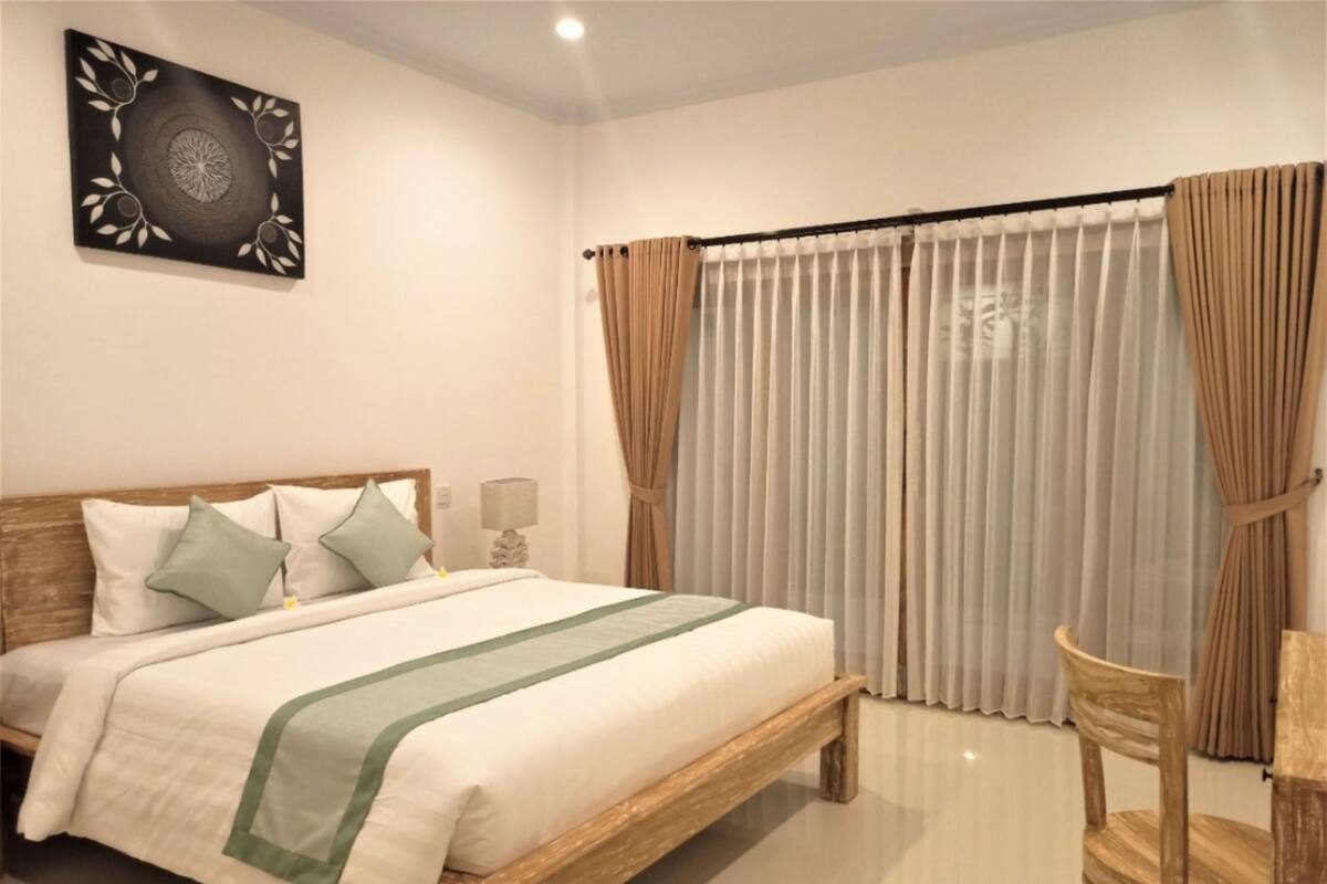 A bedroom with a wooden bed, a bedside table with a lamp, and a chair.