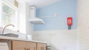 Eine kompakte Küche mit Holzschränken, einem eingebauten Backofen und einem Fenster für natürliches Licht.