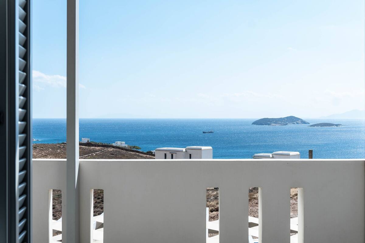 A balcony with a view of the sea, buildings, and a small island.