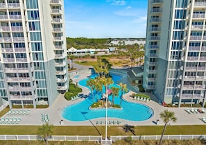 A hotel with a central swimming pool, multiple balconies, and a view of the surrounding area.