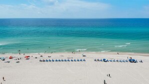 A beach with clear blue water, white sand, and blue umbrellas.