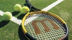 A tennis racket and balls on a green court.