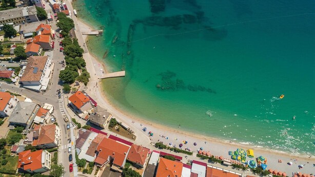 An aerial view of a coastal town with a beach, buildings, and a pier. - 1 bedroom beach front apartment in Baska (Baska)