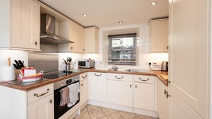 A kitchen with white cabinets, a stainless steel range hood, a microwave, and a sink. - Luxury Cottage in the Scenic Borders of Scotland (Canonbie)