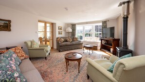 A cozy living room with a sofa, armchairs, a coffee table, and a fireplace. - Luxury Cottage in the Scenic Borders of Scotland (Canonbie)