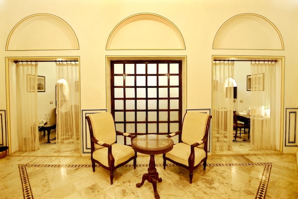 A room with a marble floor, two armchairs, a small round table, and a large window with a grid pattern. - Narain Niwas Palace (Jaipur)