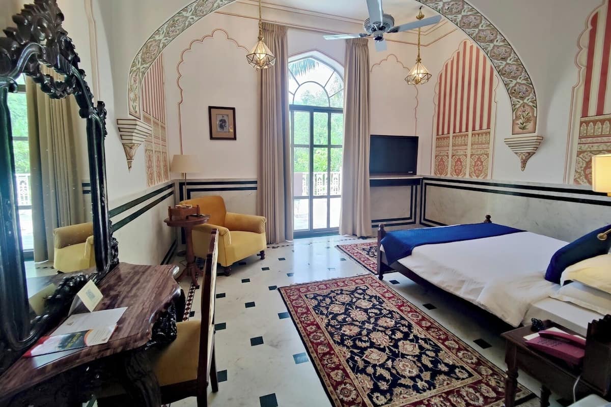 Une chambre d’hôtel équipée d’un lit, d’un bureau, d’une chaise, d’une télévision et d’une grande fenêtre.