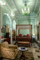 Um quarto tradicional com uma cama de dossel, uma poltrona estampada e uma mesa pequena.
