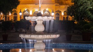 Una fuente frente a un edificio con ventanas de arco y una piscina con azulejos.