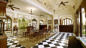 Una habitación con piso a cuadros, muebles de madera, ventiladores de techo y decoración en las paredes.