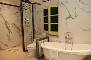Un baño con pared de mármol, bañera, inodoro y cabina de ducha.