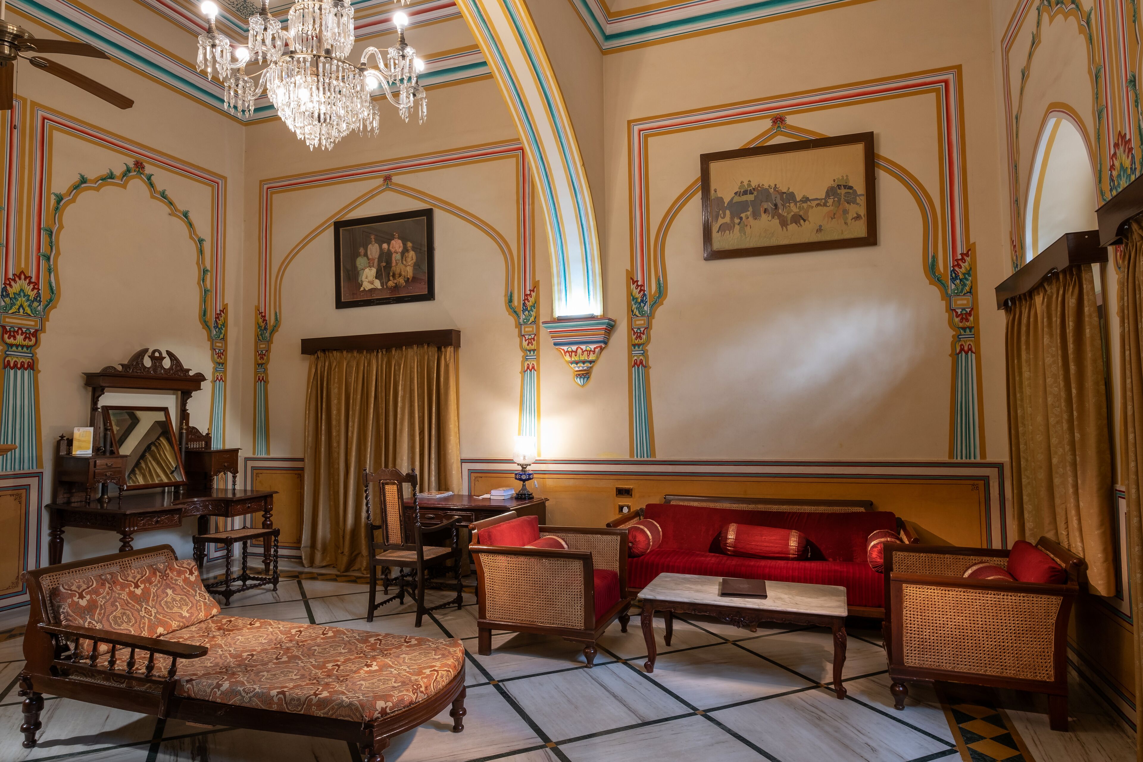 A room with a chandelier, a red sofa, and traditional decor.
