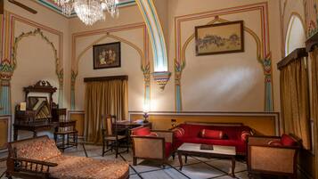 A room with a chandelier, a red sofa, and traditional decor.