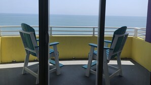 Un balcon avec deux chaises et une table, offrant une vue dégagée sur l’océan.