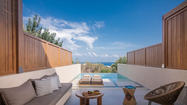 Un área lounge moderna al aire libre con piscina, mobiliario de madera y vista al mar.