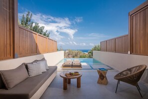 Un espace de détente extérieur moderne, doté d’une piscine, de mobilier en bois et offrant une vue sur la mer.