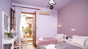 Une chambre avec deux lits, un bureau, une chaise et un balcon.
