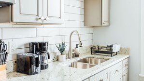 A kitchen with white cabinets, a stainless steel sink, a coffee maker, and a toaster. - 2R- ❤️ Stylish and Cozy 2BR in Logan Square! (Chicago)