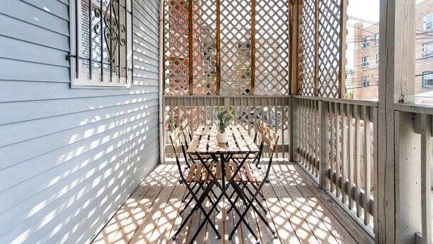 A balcony with a wooden table and chairs, a potted plant, and a lattice screen. - 2R- ❤️ Stylish and Cozy 2BR in Logan Square! (Chicago)