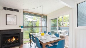 Uma sala de jantar com lareira, cadeiras azuis e uma mesa posta para seis pessoas.