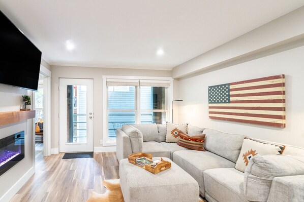 Un soggiorno moderno con un divano componibile, un televisore a schermo piatto e un grande quadro con la bandiera americana.