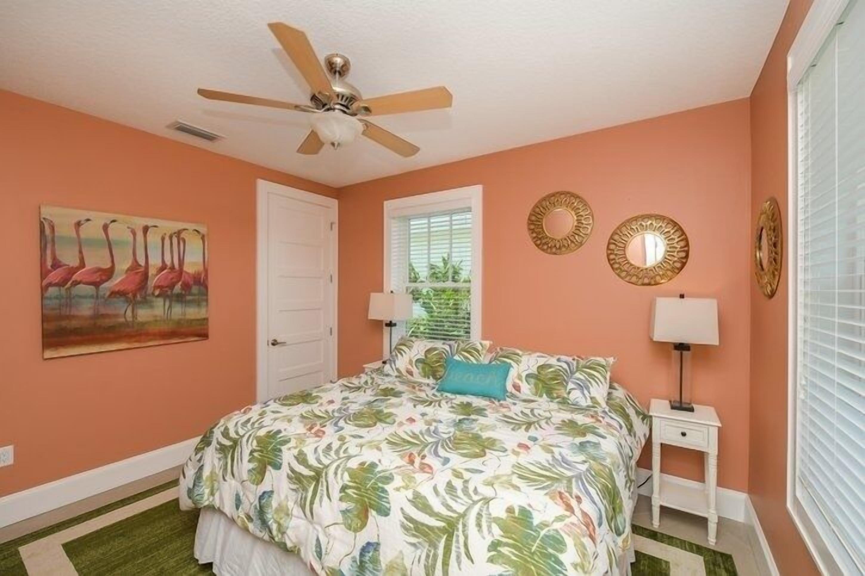 Une chambre à coucher avec un lit, un ventilateur de plafond, une fenêtre et des décorations murales.