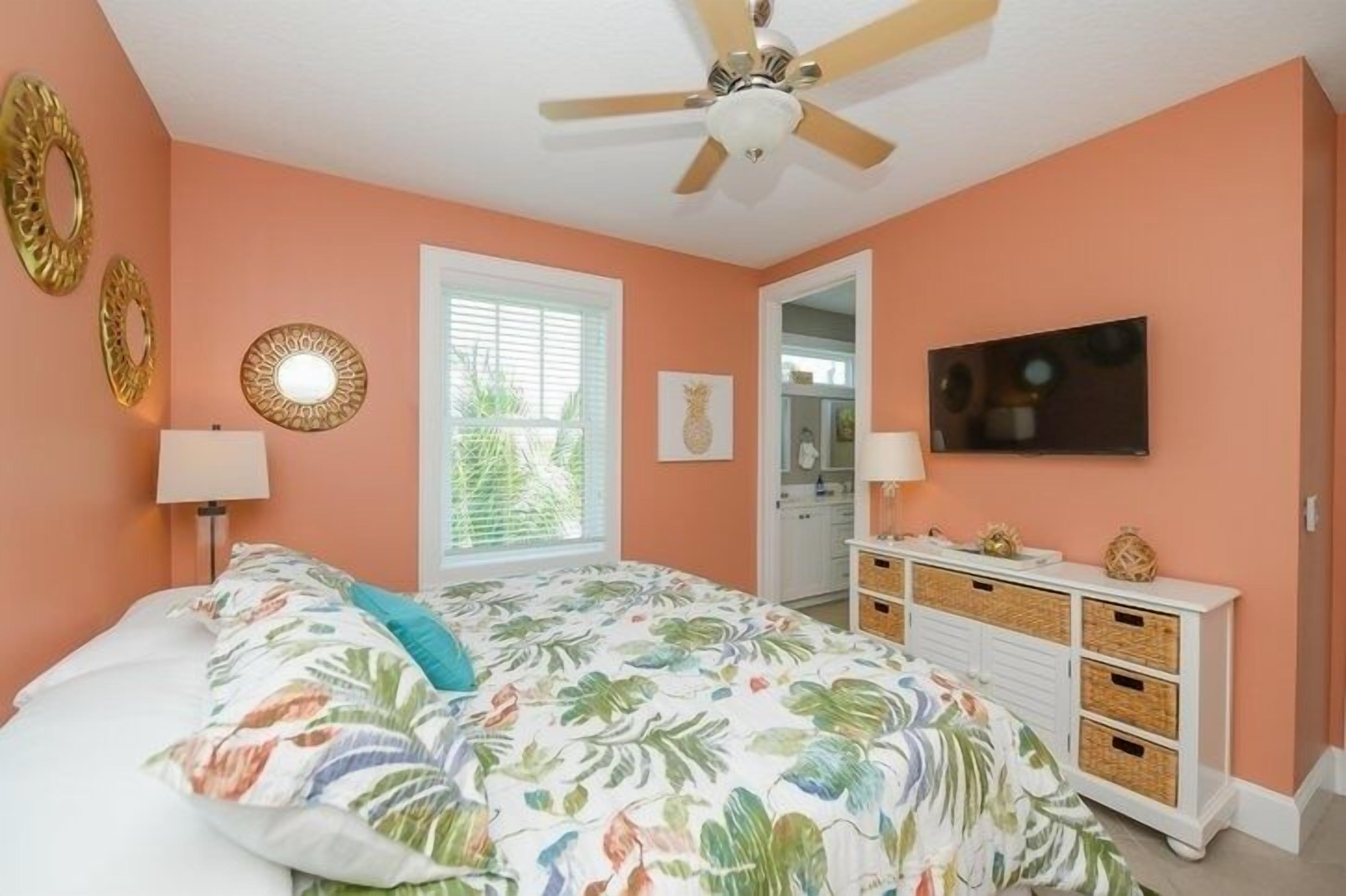A bedroom with a bed, ceiling fan, wall decor, and a dresser.