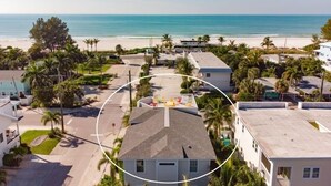 A beachfront property with multiple buildings, a parking area, and a view of the ocean. - Sunset Surf 2201 Ave C 6 Bedroom Home by RedAwning (Bradenton Beach)