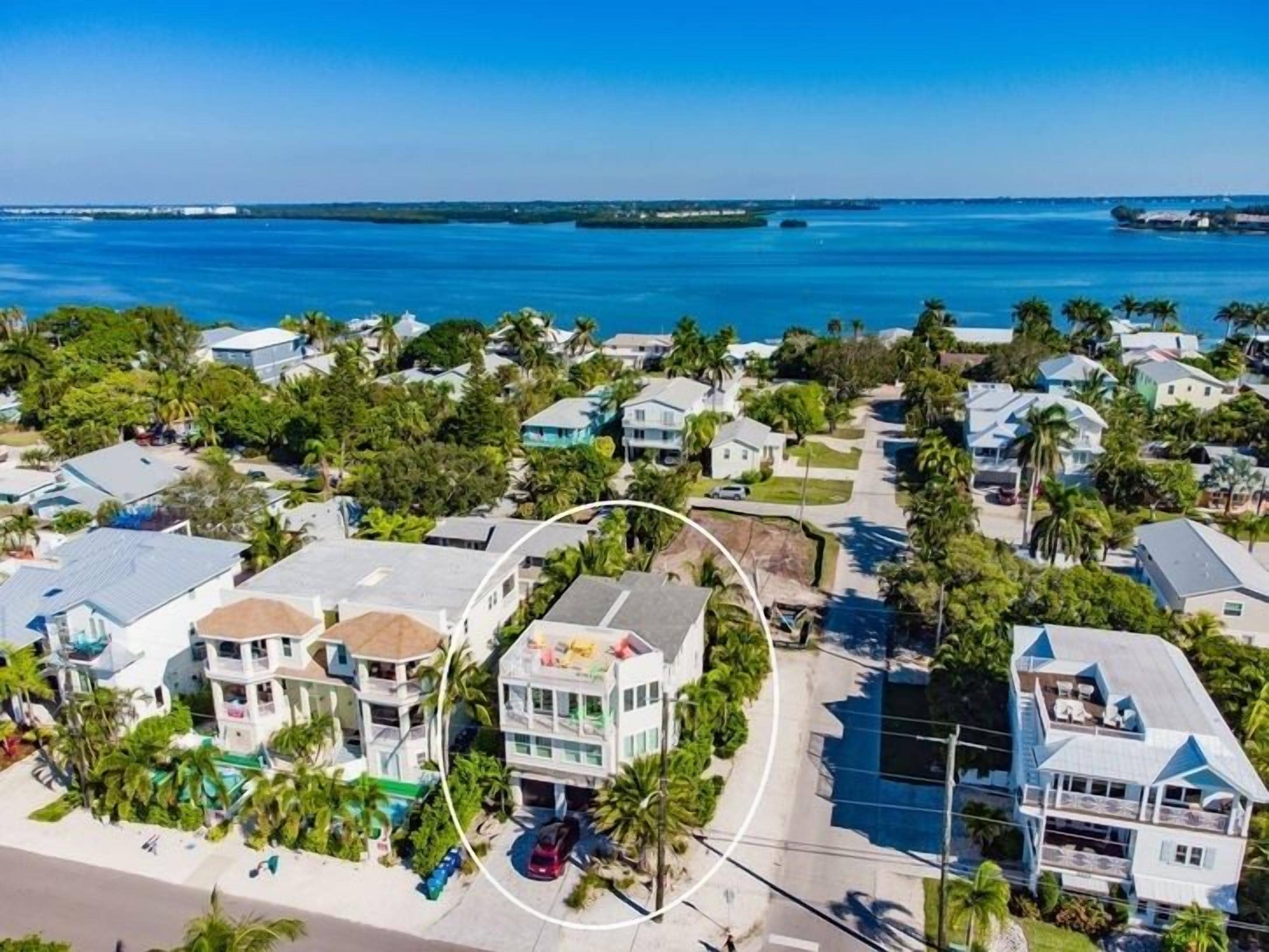 A coastal residential area with houses, palm trees, and a clear view of the ocean.