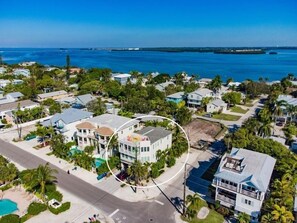An aerial view of a coastal residential area with houses, a road, and a beach. - Sunset Surf 2201 Ave C 6 Bedroom Home by RedAwning (Bradenton Beach)