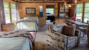 Un interior acogedor de cabaña con dos camas, un comedor y una cocina.