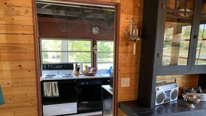 Una cocina con paredes de madera, una estufa, un lavabo y una radio.