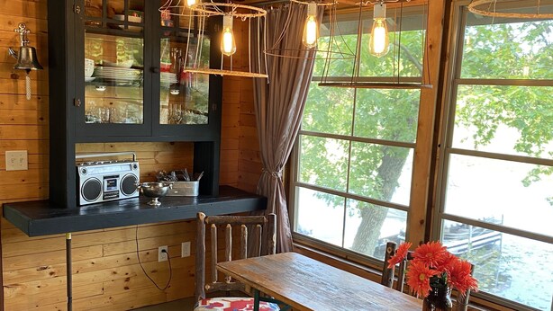 Una cocina rústica con vigas de madera, una radio antigua y un ventanal con vistas a árboles.