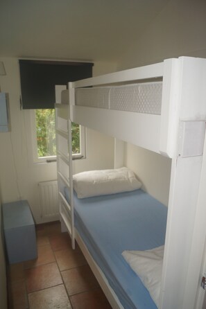 A bunk bed room with a window, a radiator, and a small desk.