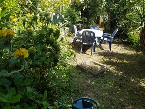Un jardín con mesa y sillas, rodeado de follaje y plantas.