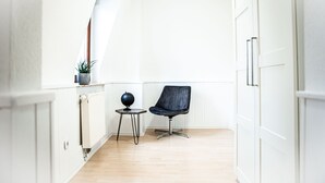 A small, bright room with a wooden floor, a black chair, a small table with a globe, and a potted plant. - House Felix Weinbergblick (Radebeul)