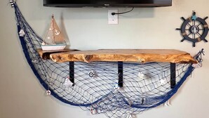 Une étagère en forme de hamac, ornée d’un volant de navire et sur laquelle est fixée une télévision murale.