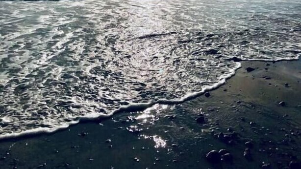 Une plage avec des vagues et un ciel partiellement nuageux.