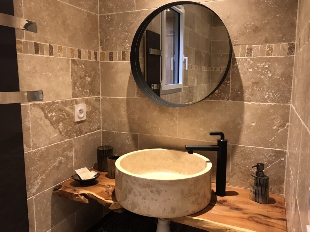 A bathroom with a round sink, a mirror, and a wooden countertop.