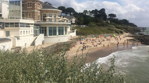 Ein Hotel an der Küste mit Blick auf den Strand, einer mehrstöckigen Struktur und einem angelegten Garten.