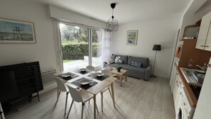 Ein zeitgemäßer Wohnraum mit Essbereich, einer Couch, einer Küche und einer großen Glasschiebetür, die auf eine Terrasse führt.