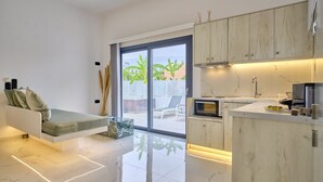 A modern kitchen with a built-in oven and microwave, a dining area with a bench, and a sliding glass door leading to a balcony with plants.