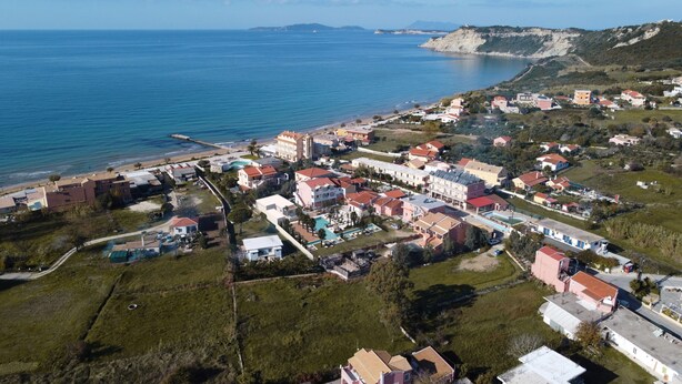 Vue aérienne d’une zone résidentielle c ôtière, avec des maisons, une plage et une vue dégagée sur la mer.