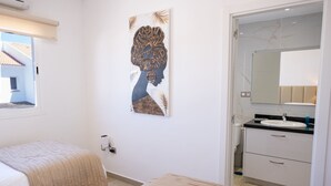 Une chambre avec deux lits, une salle de bain avec un miroir et un lavabo, et une œuvre d’art accrochée au mur.