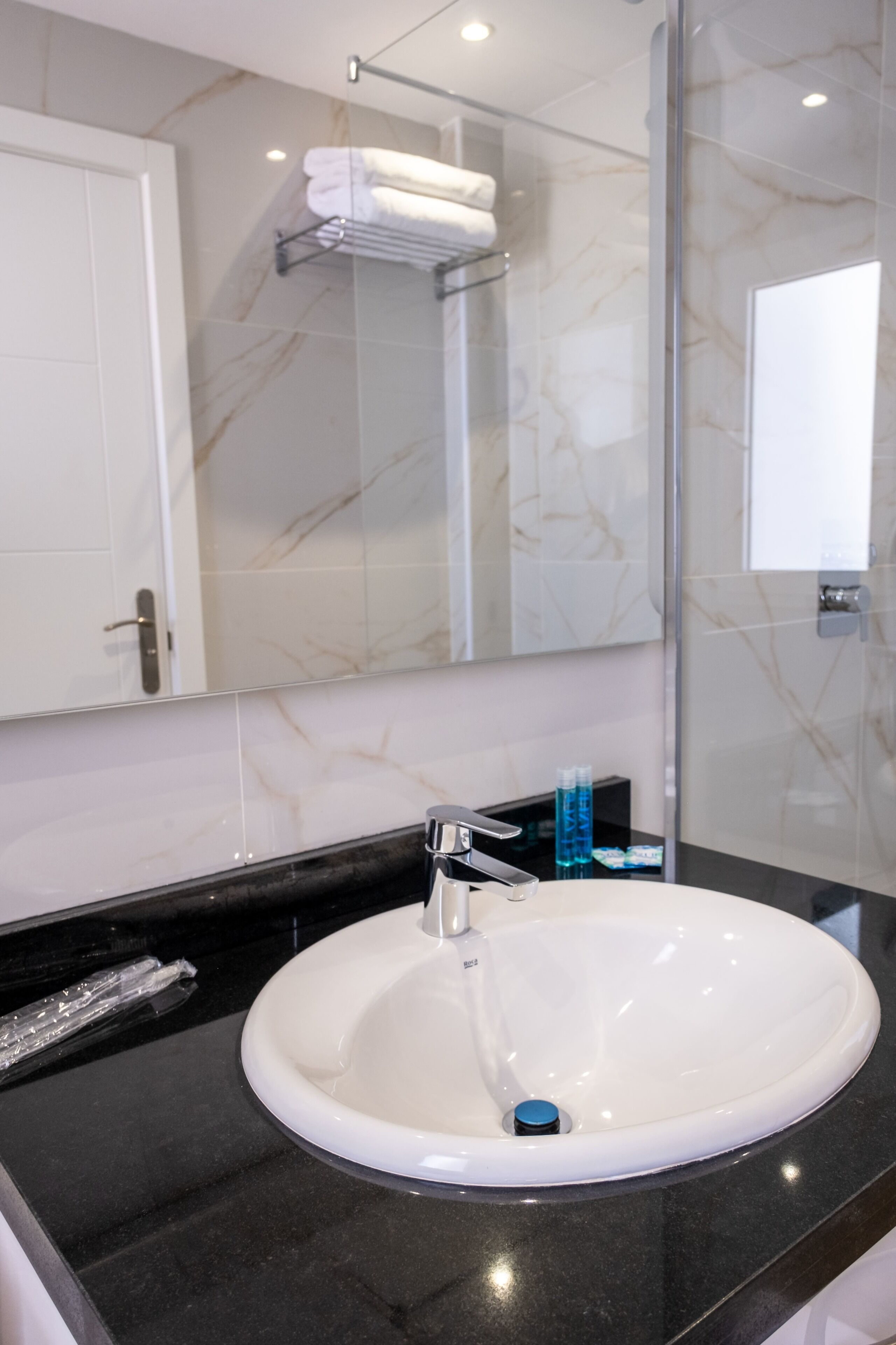 A bathroom with a white sink, a mirror, and a towel rack.