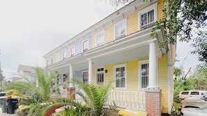 A two-story yellow house with a porch, a brick foundation, and a small garden with palm trees. - Craftsman-style Starland District Gem ☆ Home Office & Back Yard ☆ Pet-Friendly (Savannah)
